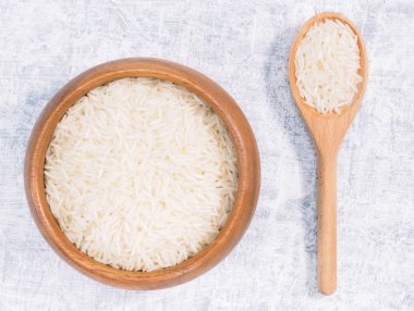 Kahverengi ahşap kase ve kaşık içinde Hint uzun taneli Basmati pilavı.