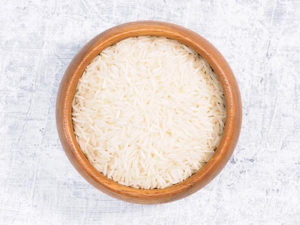 Hindistan uzun tahıllı Basmati pirinci kahverengi ahşap kasede beyaz tezgahta. — Stok fotoğraf