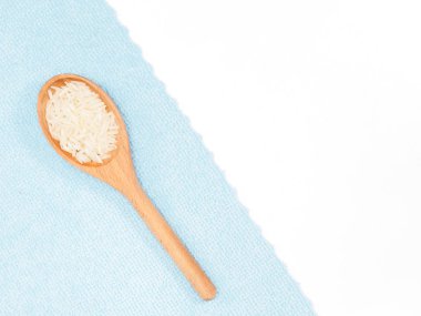 Beyaz ve mavi kumaş zemin üzerinde, tahta kaşıkla yapılmış Hint uzun tahıllı Basmati pirinci. Hint mutfağı, ayurveda, naturopati kavramı.