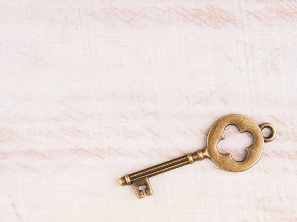 Old bronze key on light brown wooden background with copy space