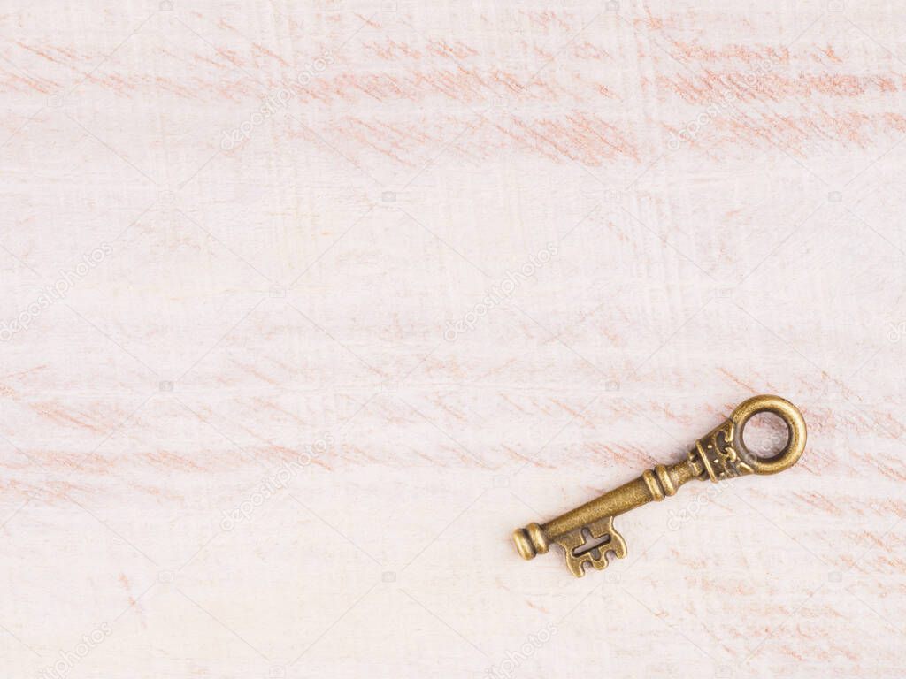 Old bronze antique key on light brown wooden background with copy space
