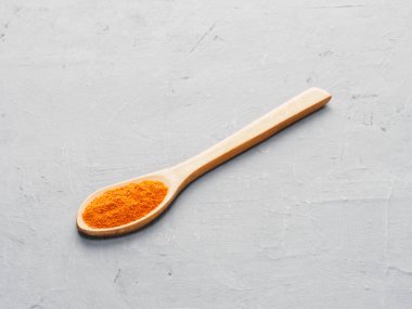 Spice red chili pepper in wooden spoon on gray concrete background. Indian cuisine, ayurveda, naturopathy concept