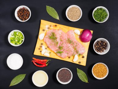 Tahta kesim tahtası, sarımsak, kimyon (jeera), tuz, rezene, baharat, çemen otu, hardal tohumu, yağ, yeşil ve kırmızı soğan üzerinde dilimlenmiş hindi filetosu, siyah ahşap zemin üzerinde karanfil. Sağlıklı yeme kavramı