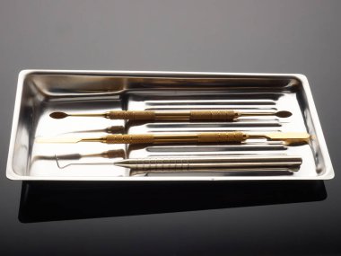 Gri gradyan arka planda diş tepsisindeki tıbbi aletler