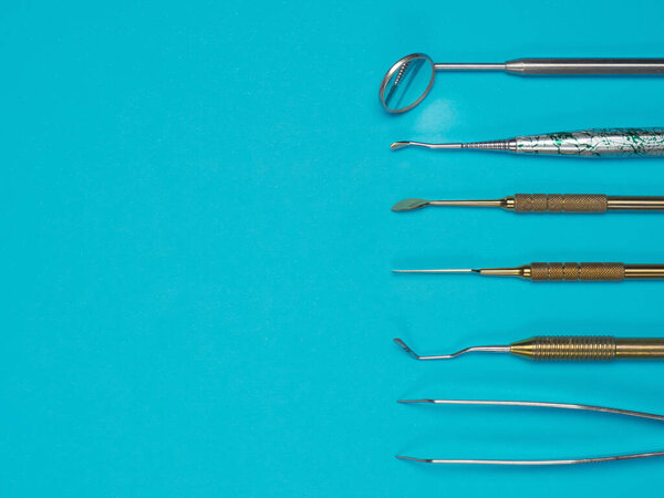 Профессиональные зубные инструменты на синем фоне. Концепция стоматологического здоровья
