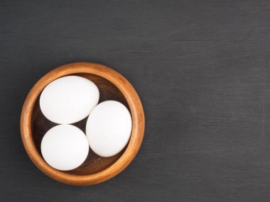 Tahta kasede çiğ tavuk yumurtası ve siyah ahşap arka planda fotokopi alanı. Organik gıda konsepti