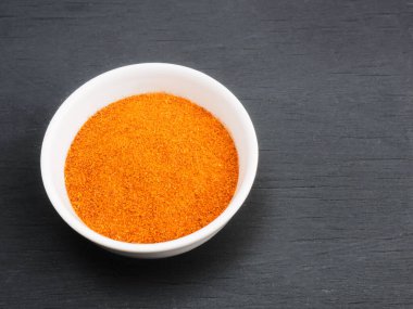 Siyah ahşap arka planda beyaz seramik kasede kırmızı biber. Sağlıklı beslenme ve organik gıda konsepti