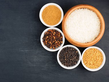 Basmati uzun pirinç, karabiber, masala tozu, çemen otu, siyah ahşap arka planda karanfil. Sağlıklı beslenme ve organik gıda konsepti