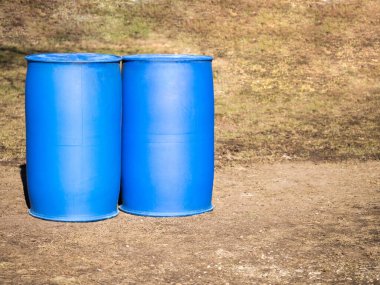 İki mavi plastik fıçı yerde duruyor. Sıvı depolama konsepti