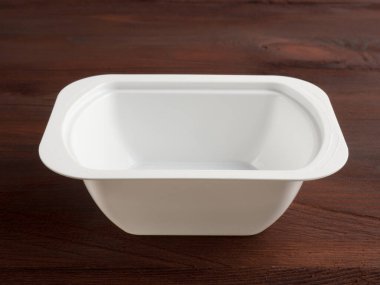 Kahverengi ahşap arka planda plastik beyaz bir banka.