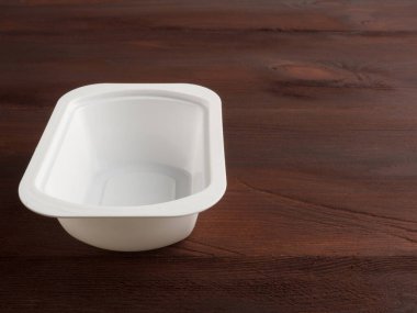 Kahverengi ahşap arka planda plastik beyaz bir banka.