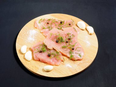 Dilimlenmiş hindi fileto, sarımsak, tuz, rezene, hepsi siyah ahşap zemin üzerine baharat. Sağlıklı yeme kavramı