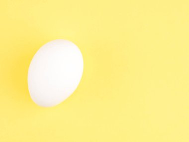 Sarı arka planda beyaz bir tavuk yumurtası. Sağlıklı yeme kavramı