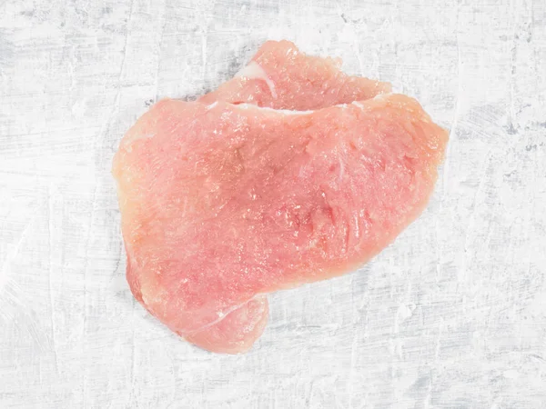 Sliced pieces of meat turkey game filet on white concrete background. Healthy eating concept