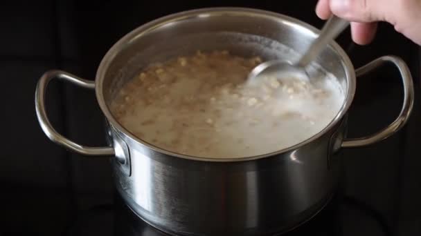 牛乳でオートミールを調理 オートミールフレークをスプーンで混ぜます 料理のコンセプト — ストック動画