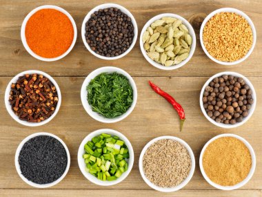 Baharat seti: kırmızı biber, masala, karabiber, kimyon, çemen otu, karanfil, yeşil kakule, rezene, ahşap zemin üzerinde soğan. Sağlıklı yeme kavramı