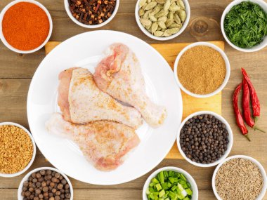 Bambu kasesinde çiğ tavuk budu ve baharat seti: kırmızı biber, masala, karabiber, kimyon, çemen otu, karanfil, yeşil soğan, rezene. Sağlıklı yeme kavramı