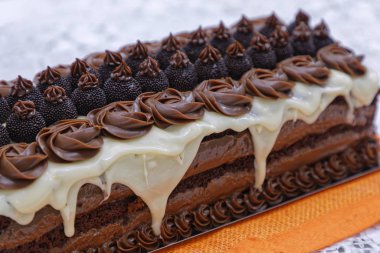 sponge chocolate cake with white glaze and candies on kitchen background