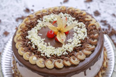 Karamelli kapuçino kek katmanlı, moka kaplı, kiraz süslemeli ve fisali soslu. 