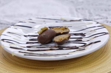 Badem ezmesi şekerleri beyaz tabaklar ve tahtadan fındıklı sütlü çikolata kaplı.