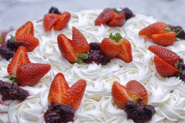 Krem şantili mascarpone kekinin üzerine beyaz tabakta çilek ve böğürtlen reçeli.