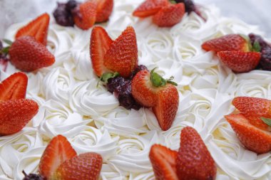 Krem şantili mascarpone kekinin üzerine beyaz tabakta çilek ve böğürtlen reçeli.