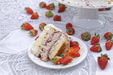 Beyaz tabakta yoğunlaştırılmış süt kaplı çilekli kek dilimi 