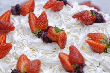 Krem şantili mascarpone kekinin üzerine beyaz tabakta çilek ve böğürtlen reçeli.