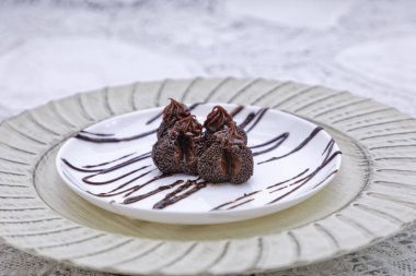 Koyu çikolatalı pralinler mutfak arka planındaki beyaz tabaklarda.