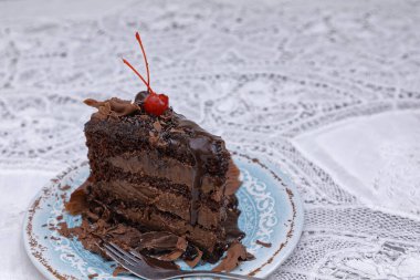 dark chocolate piece of cake with chocolate glaze on blue plate