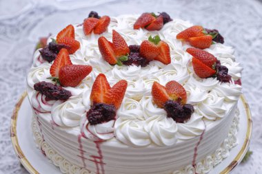 Krem şantili mascarpone kekinin üzerine beyaz tabakta çilek ve böğürtlen reçeli.