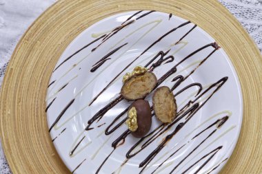 Badem ezmesi kaplı şekerler sütlü çikolata ve tahtadan fındıklar ve beyaz tabaklar