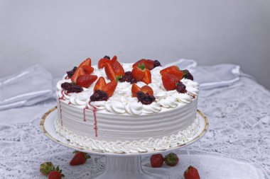white creamy cake with whipped cream and strawberries on white plate