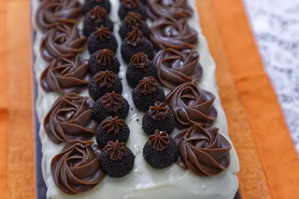 带有白色釉料的海绵巧克力蛋糕和厨房背景的糖果 — 图库照片
