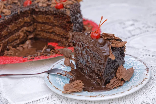 ブルーソーサーにチェリーとブラウンチョコレートペストリーケーキのスライス — ストック写真