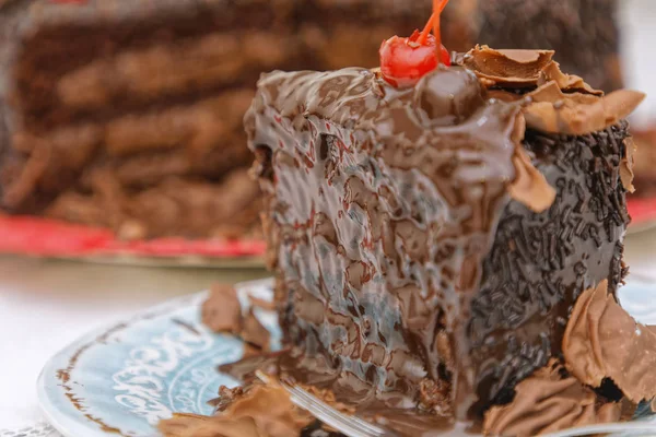 チョコレートバタークリームとチョコレートケーキのスライスは フォークでブルーソーサーにチェリーで飾られています — ストック写真