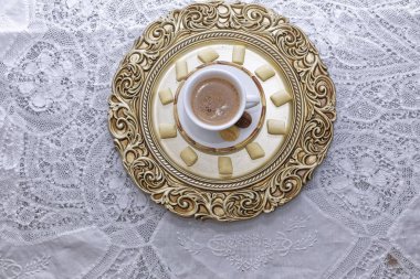 Siyah kahve, beyaz ve altın tabakta bisküvi. 