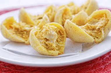 Pembe peçetede, ahşap tabakta tavuk etli peynirli çörekler.