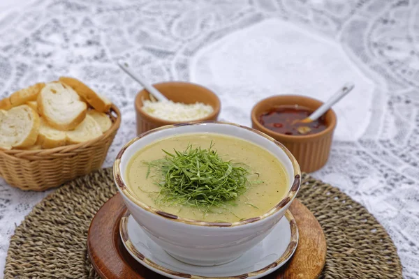 corn chowder soup with greens and basket of bread slices with sauces