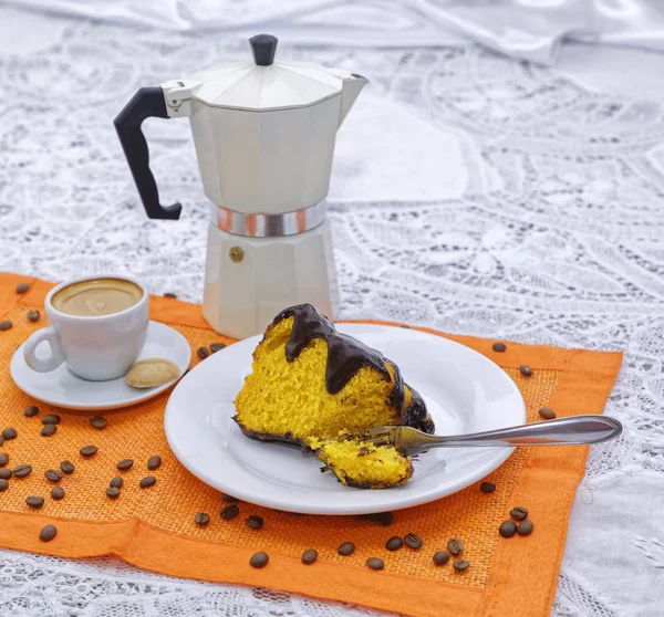 yellow lemon cake slice with cup of strong coffee and coffee kettle on orange napkin with coffee beans