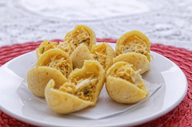 Pembe peçetede, ahşap tabakta tavuk etli peynirli çörekler.