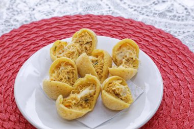 Pembe peçetede, ahşap tabakta tavuk etli peynirli çörekler.