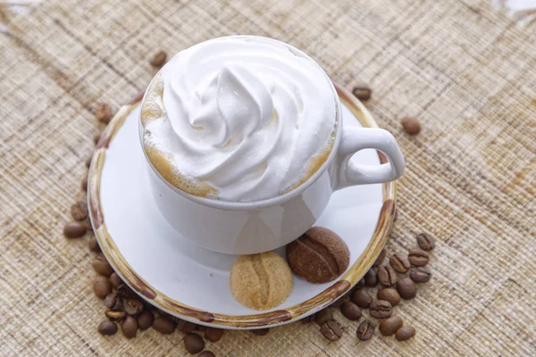Filiżanka Cappuccino Bitą Śmietaną Herbatnikami Białym Talerzu Tłem Ziaren Kawy — Zdjęcie stockowe