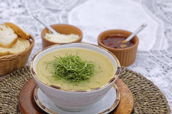 corn chowder soup with greens and basket of bread slices with sauces