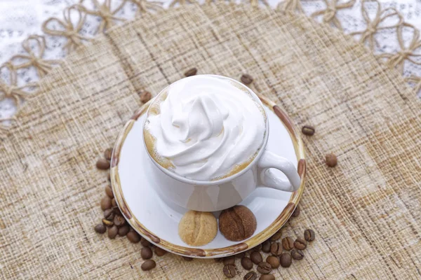 一杯卡布奇诺咖啡 白盘上夹着奶油和饼干 背景为咖啡豆 — 图库照片