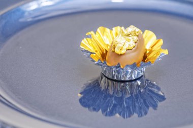 Sütlü çikolatalı şeker. Mavi tabakta altın fındıklı. 