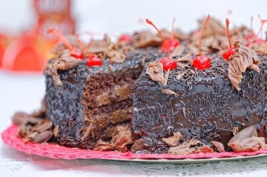 Çikolatalı pastanın üstüne kirazla süslenmiş tereyağlı çikolata.