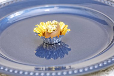 Sütlü çikolatalı şeker. Mavi tabakta altın fındıklı. 