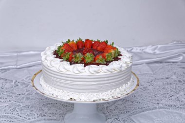 Krem şantili beyaz pasta ve beyaz mutfak masasında çilek.