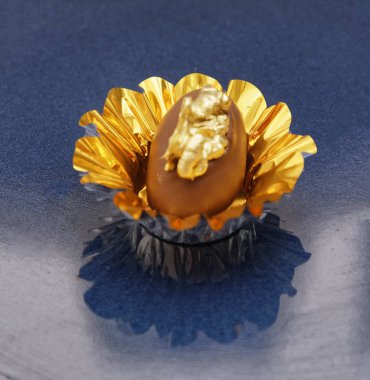 Sütlü çikolatalı şeker. Mavi tabakta altın fındıklı. 